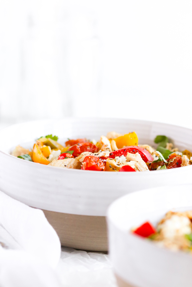 Close-up of Chicken Cauliflower Rice Bowl in stoneware bowls ext to white napkins and hammered silverware.