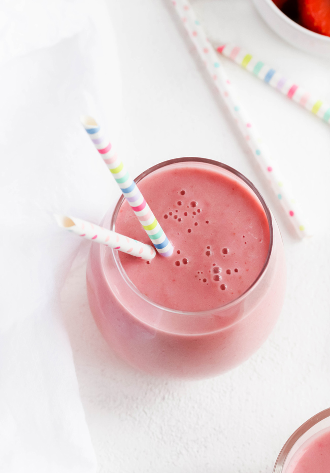 Dairy-Free Vanilla Strawberries and Cream Smoothie in a drinking glass with paper straws.